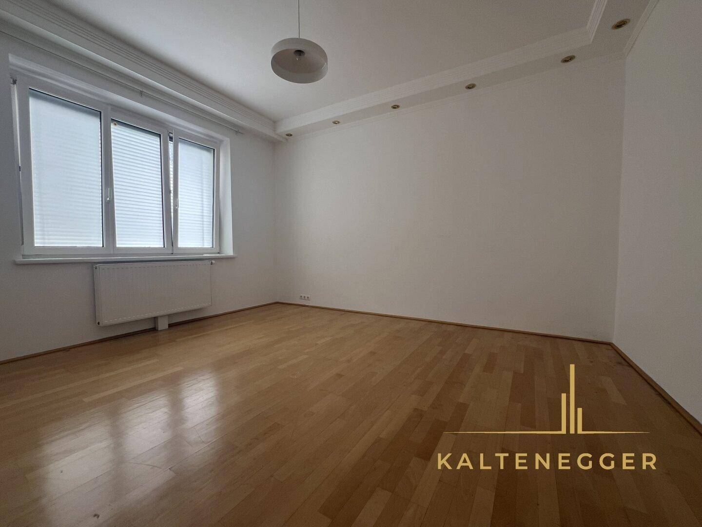 Leeres Zimmer mit Parkettboden, großen Fenstern und einem Heizkörper, ideal zur individuellen Gestaltung.