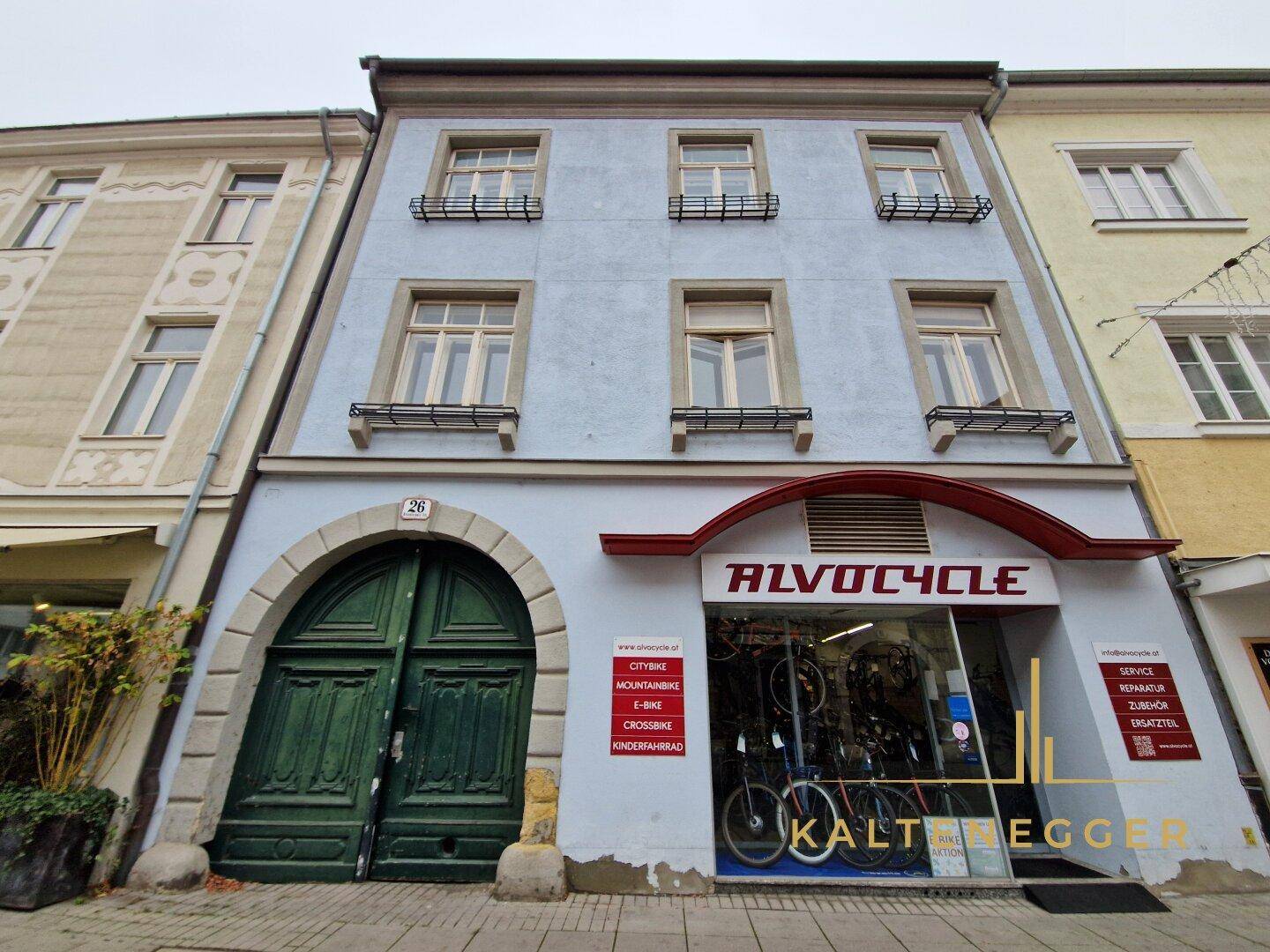 Die gesamte Fassade des historischen Gebäudes mit mehreren Stockwerken und einem Geschäft im Erdgeschoss.