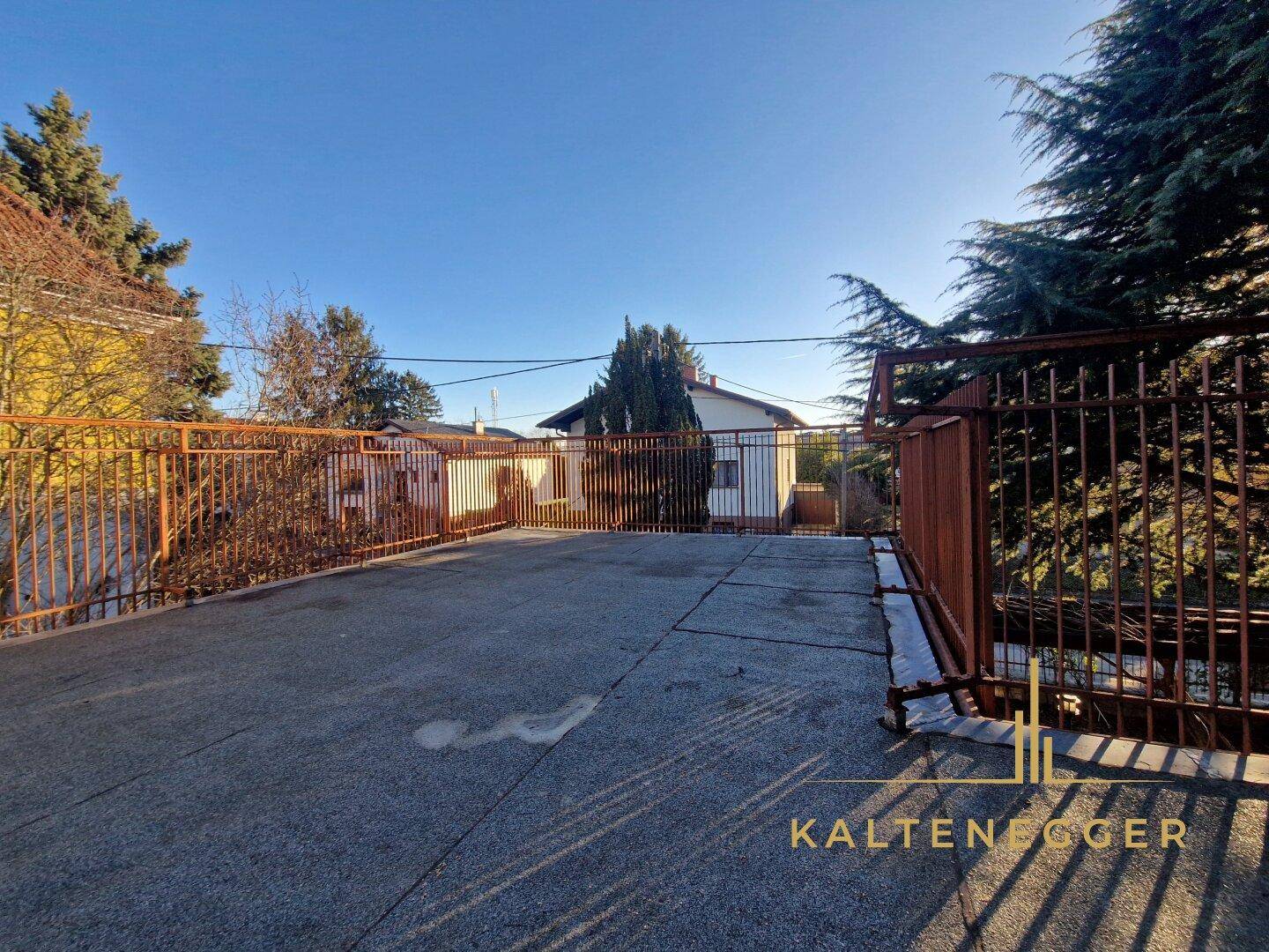 Geräumige Dachterrasse mit Metallgeländer und weitem Blick über die umliegende Wohngegend.