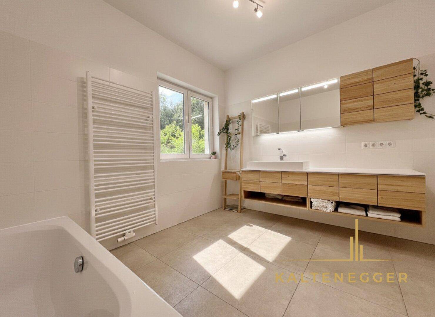 Helles Badezimmer mit Badewanne, Holzwaschtisch und beheiztem Handtuchhalter.