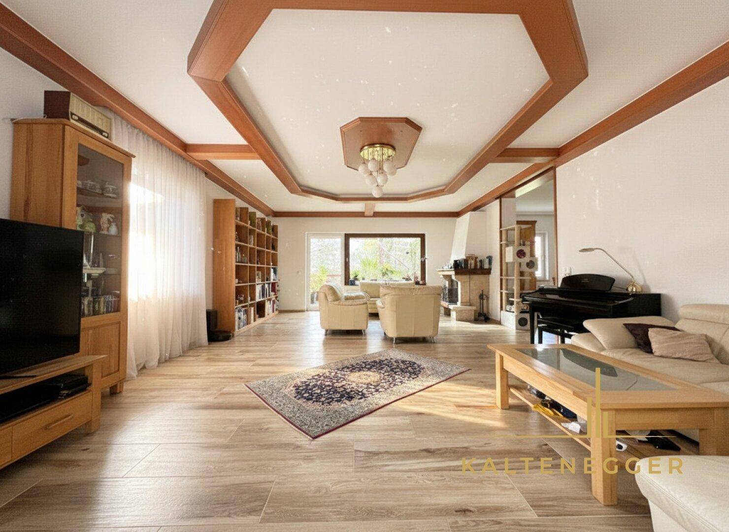 Geräumiges Wohnzimmer mit Holzbalkendecke, Kamin und Parkettboden.