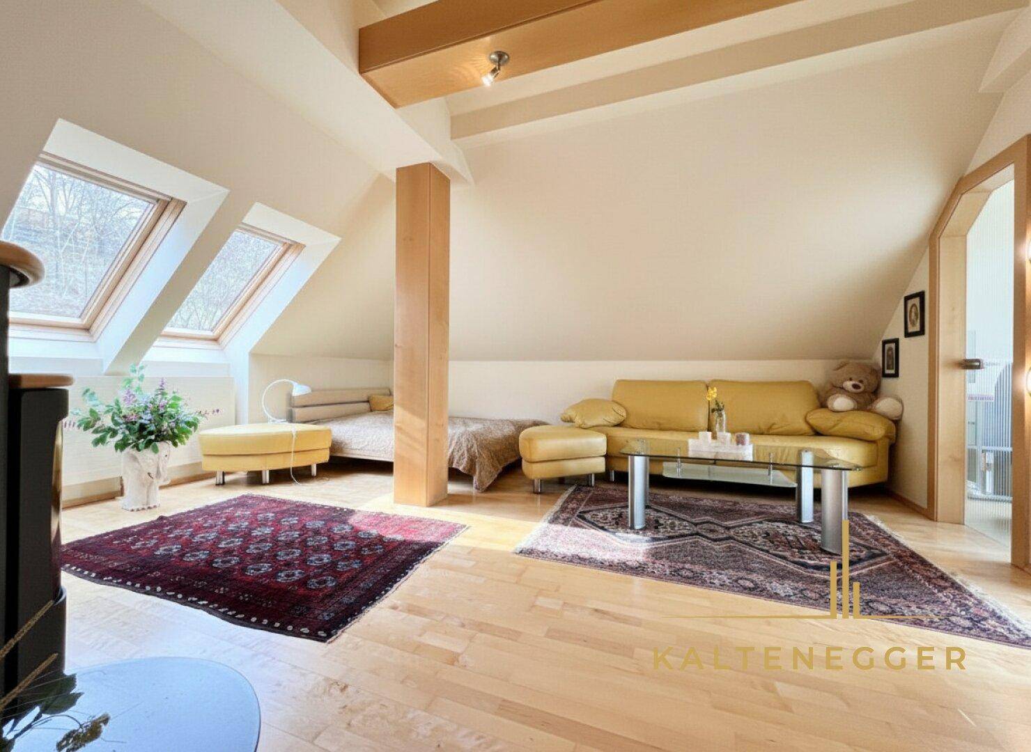 Gemütliches Schlafzimmer im Dachgeschoss mit Holzboden, Dachfenstern und Sofa.