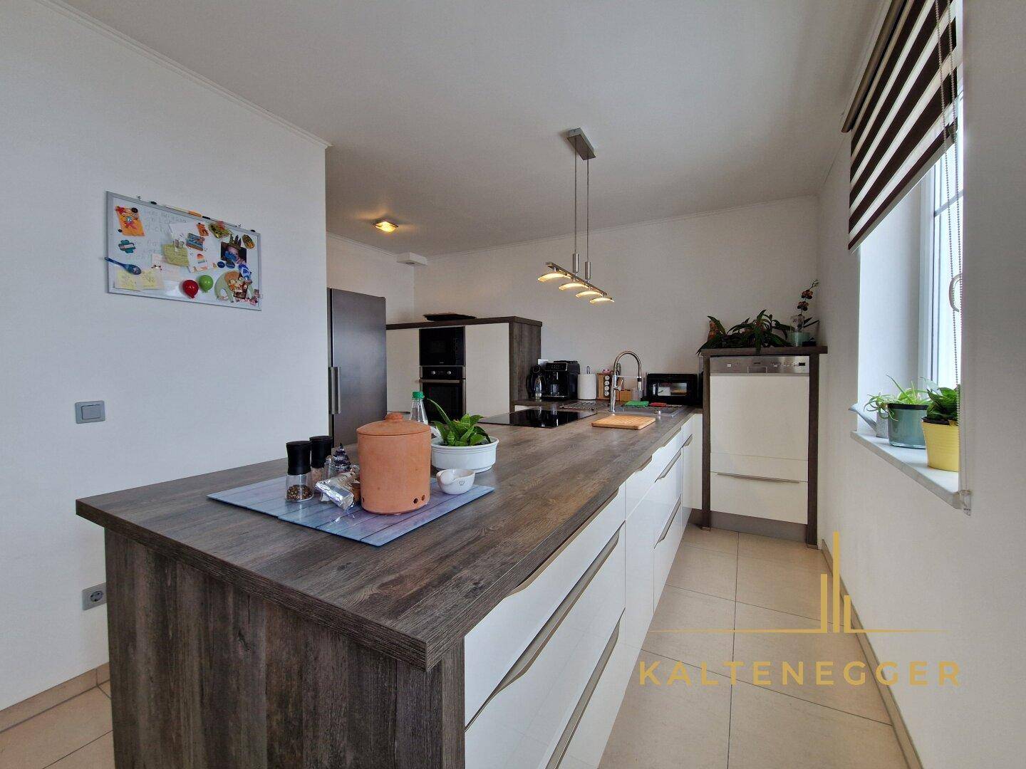 Moderne Küche mit Holz-Arbeitsplatte, weißen Schränken und integrierten Geräten.