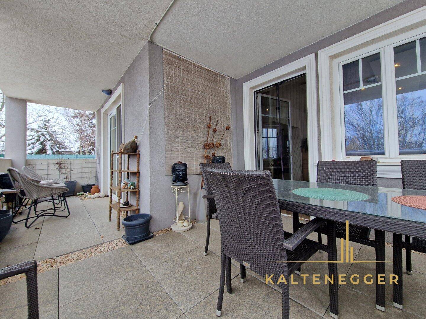 Große überdachte Terrasse mit Outdoor-Möbeln und Blick ins Grüne, ideal zum Entspannen.