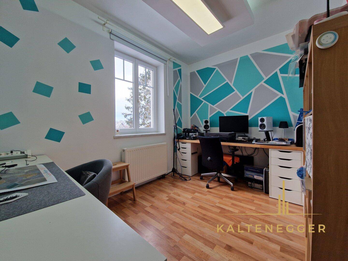 Helles Arbeitszimmer mit Holzboden, Schreibtisch und kreativer Wandgestaltung in Blau- und Grautönen.