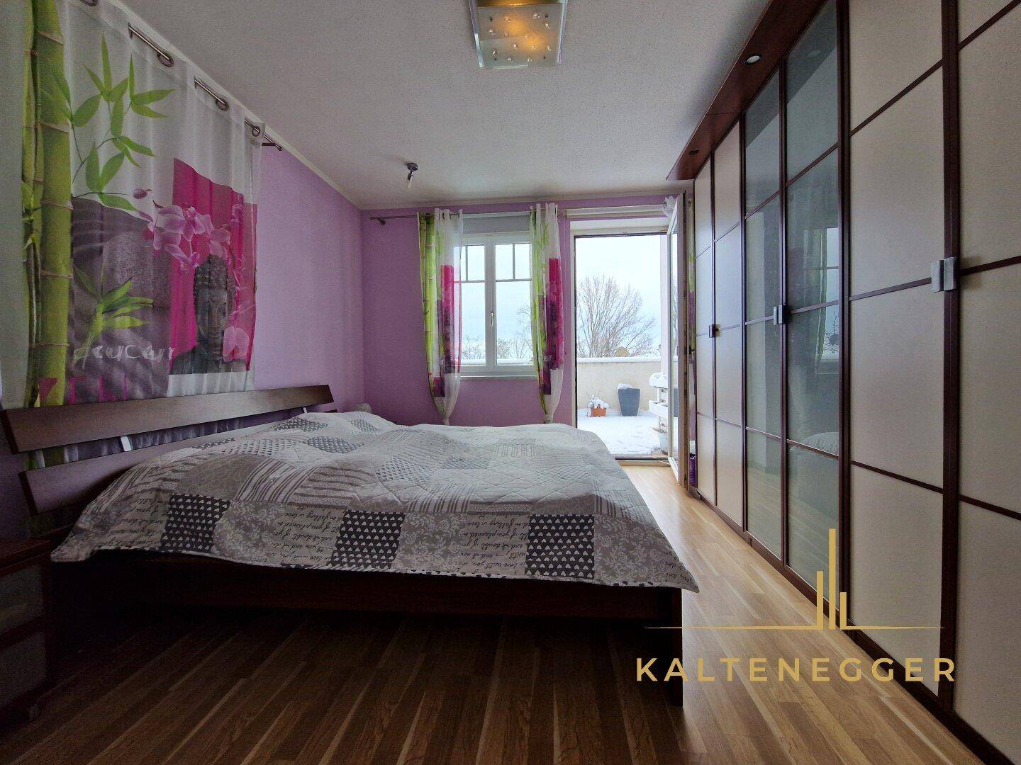 Schlafzimmer mit lila Wänden, Holzboden und Zugang zu einem Balkon oder einer Terrasse.