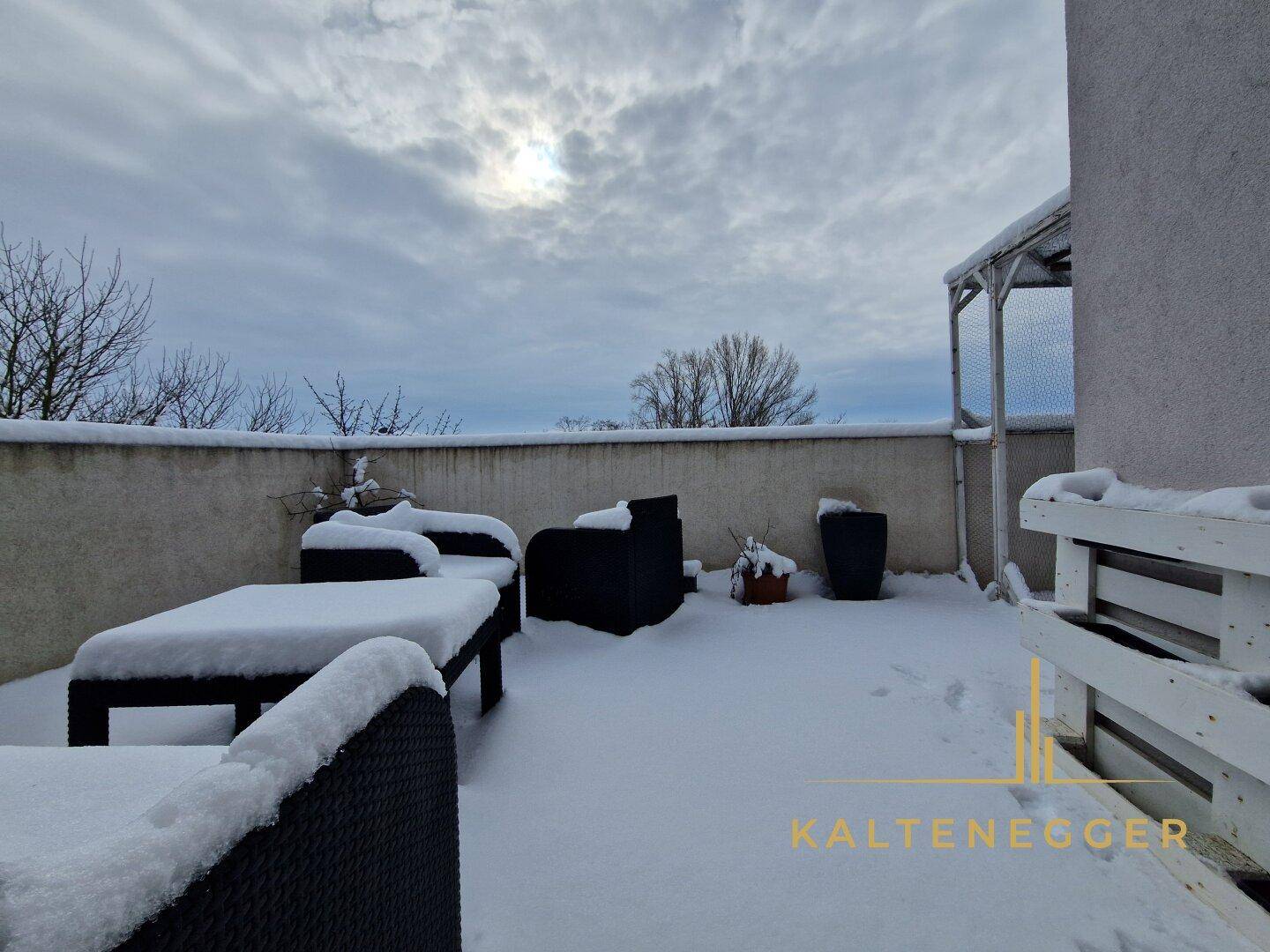 Terrasse im Winter mit Schnee bedeckten Gartenmöbeln und einer ruhigen Atmosphäre.