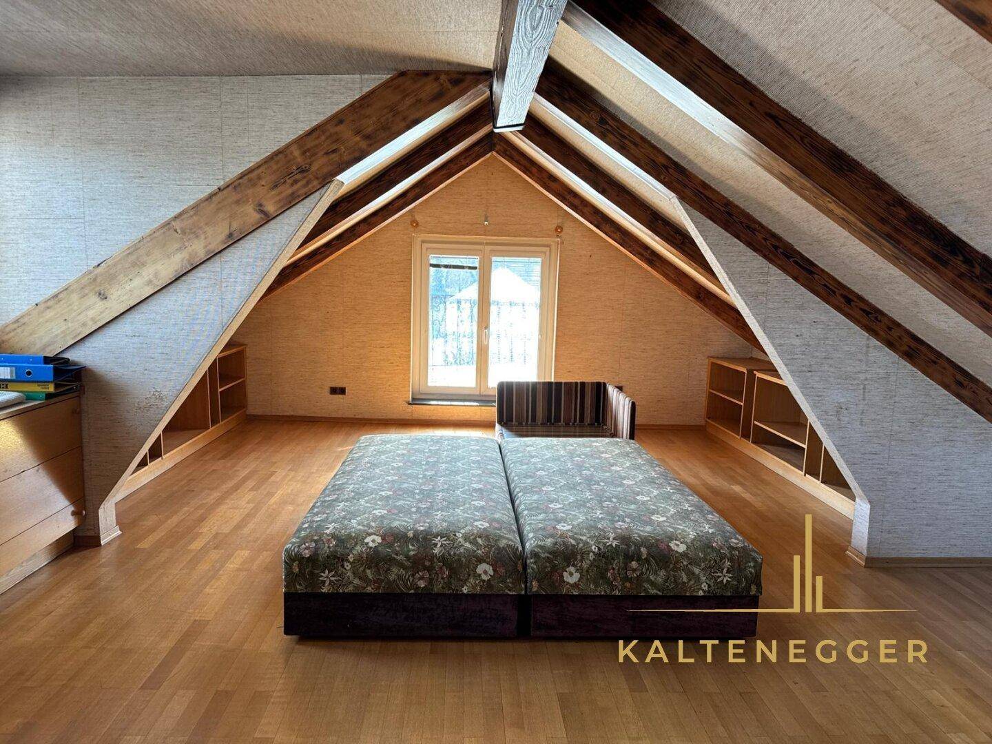 Geräumiger Dachboden mit Holzbalken, Dachschrägen und einem Fenster, vielseitig nutzbar.