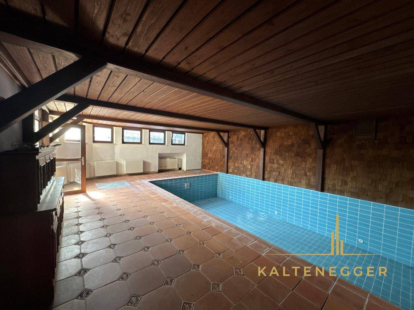 Innenpoolbereich mit Holzbalkendecke und Terrakotta-Fliesenboden, ideal für Sport und Entspannung.