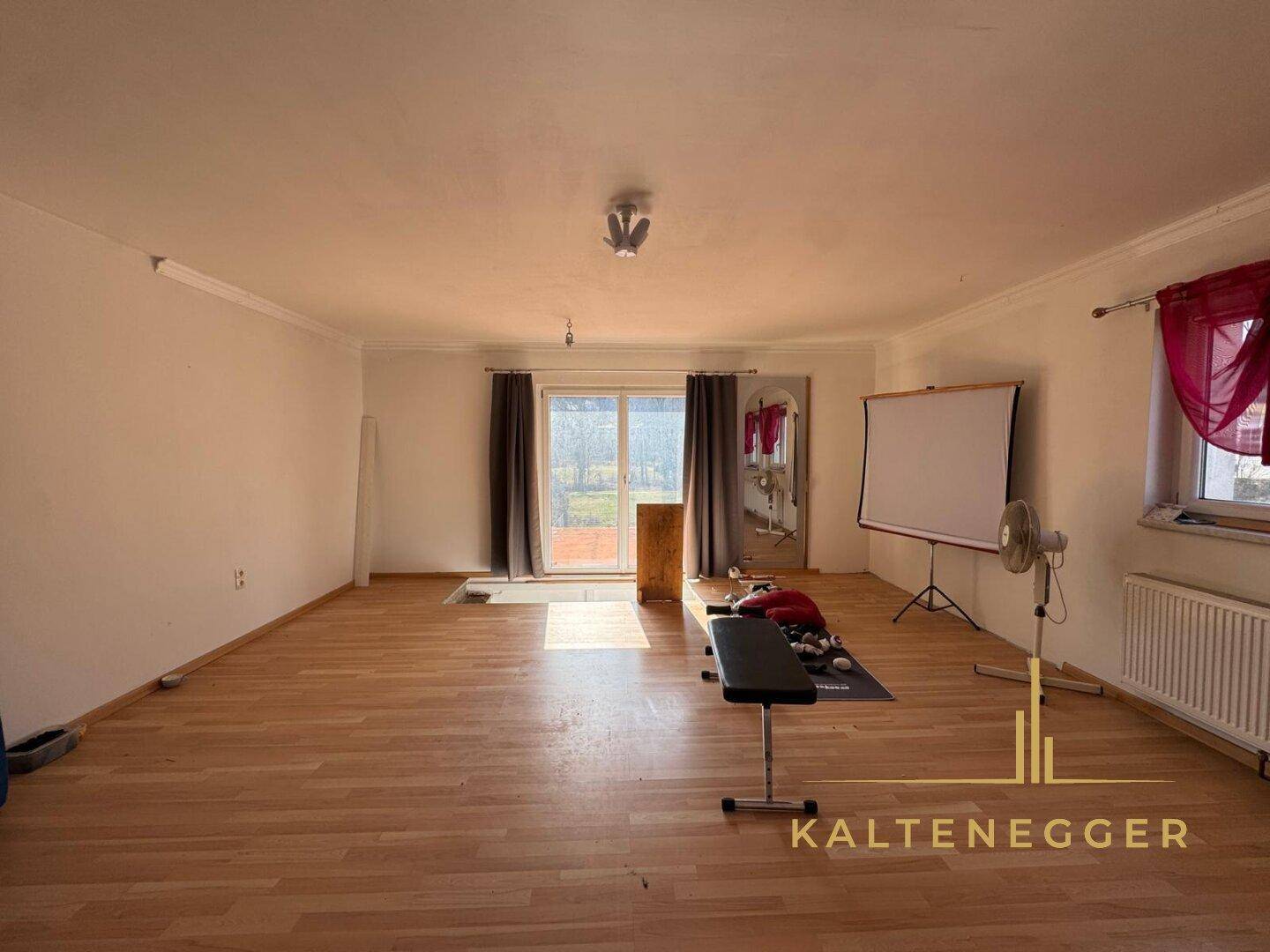 Geräumiger Wohnraum mit Parkettboden und Zugang zum Garten, vielseitig nutzbar.
