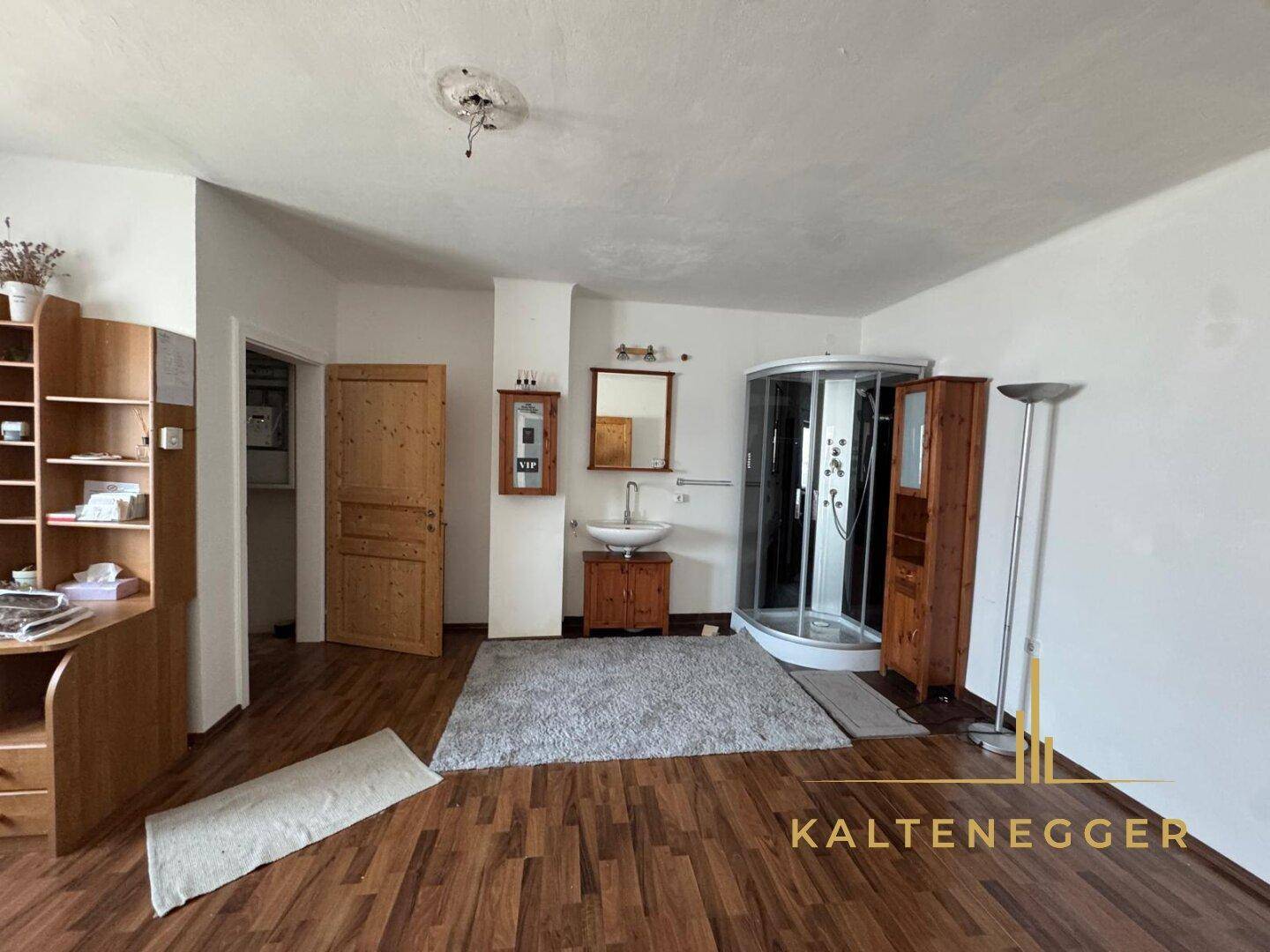 Schlafzimmer mit Holzboden, integriertem Waschbecken und Duschkabine.