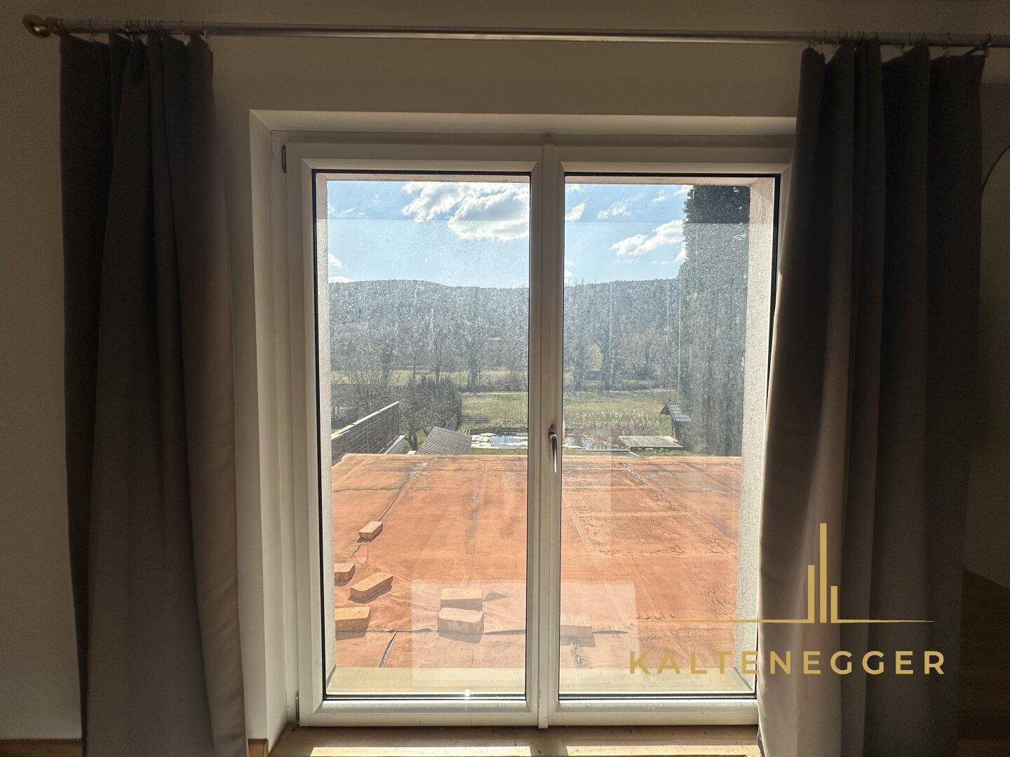 Blick aus dem Fenster auf die umliegende Landschaft und den blauen Himmel.