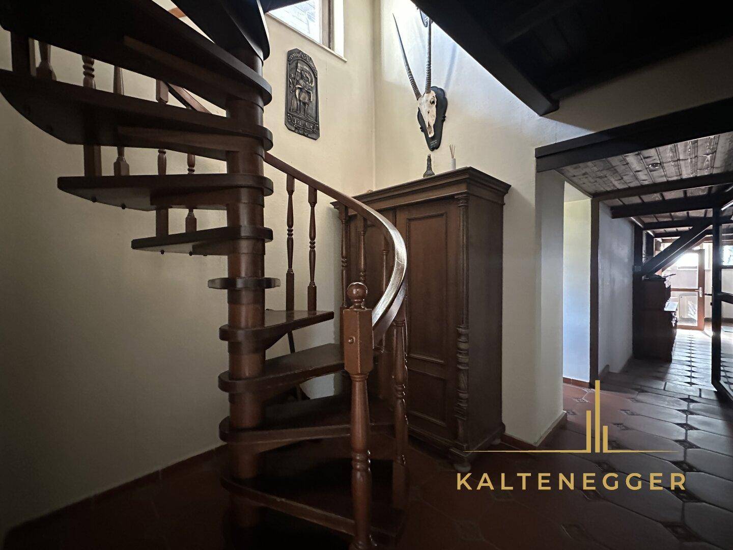 Eleganter Flur mit einer hölzernen Wendeltreppe und traditioneller Dekoration.