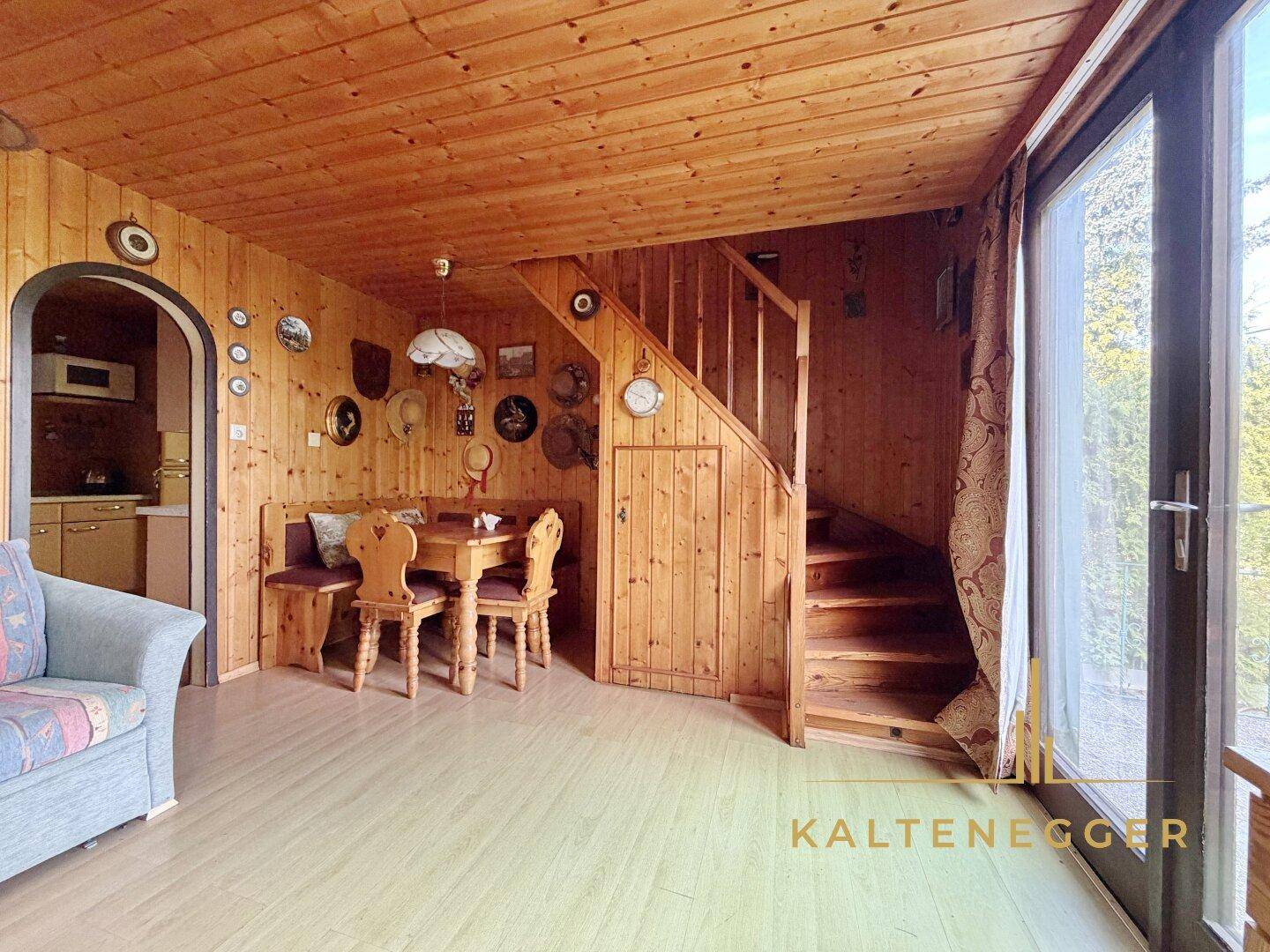 Heller Wohn- und Essbereich mit Holztäfelung, traditionellen Möbeln und Zugang zur Terrasse.