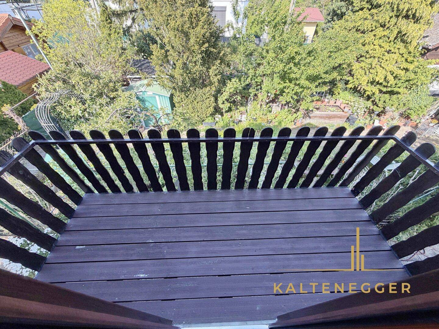 Blick von oben auf den Holzbalkon mit rustikalem Geländer und die darunterliegende Umgebung.