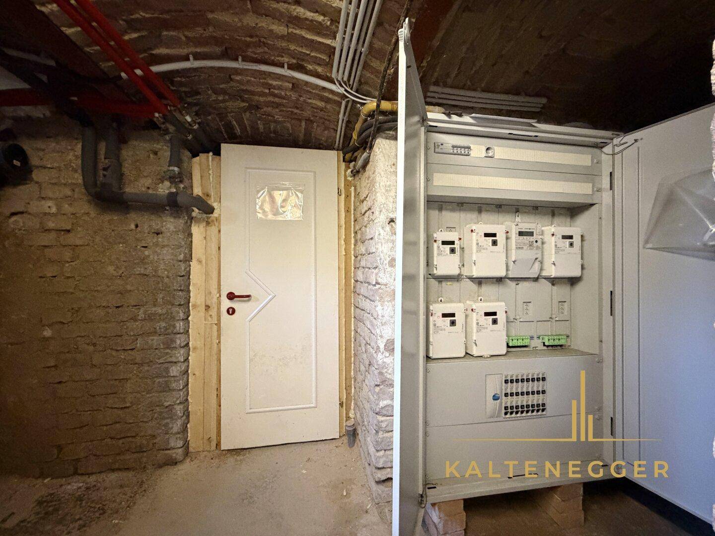 Kellerraum mit freiliegenden Ziegelwänden und einem modernen Stromverteilerkasten.