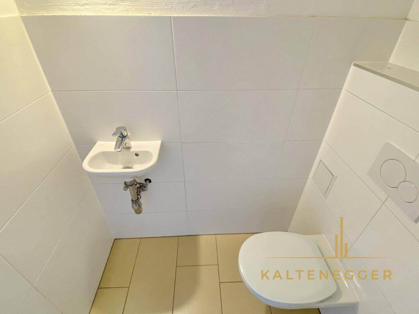 Kleines Gäste-WC mit wandhängender Toilette und kleinem Waschbecken.