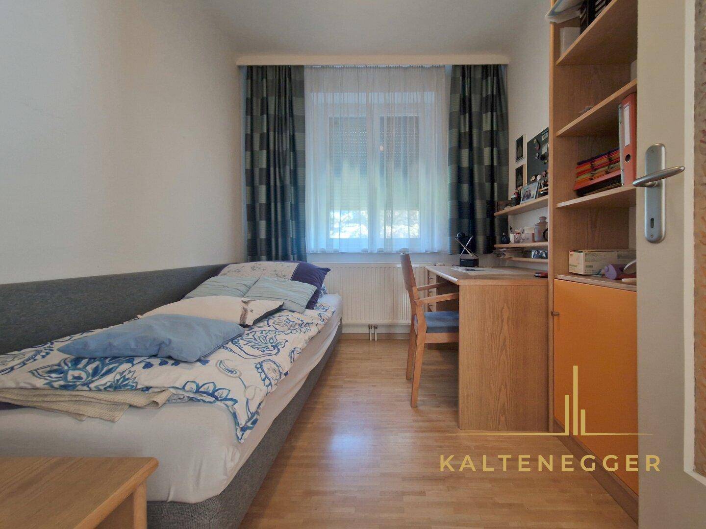 Kleines Schlafzimmer mit Einzelbett, Schreibtisch und Bücherregal, ideal als Kinder- oder Gästezimmer.