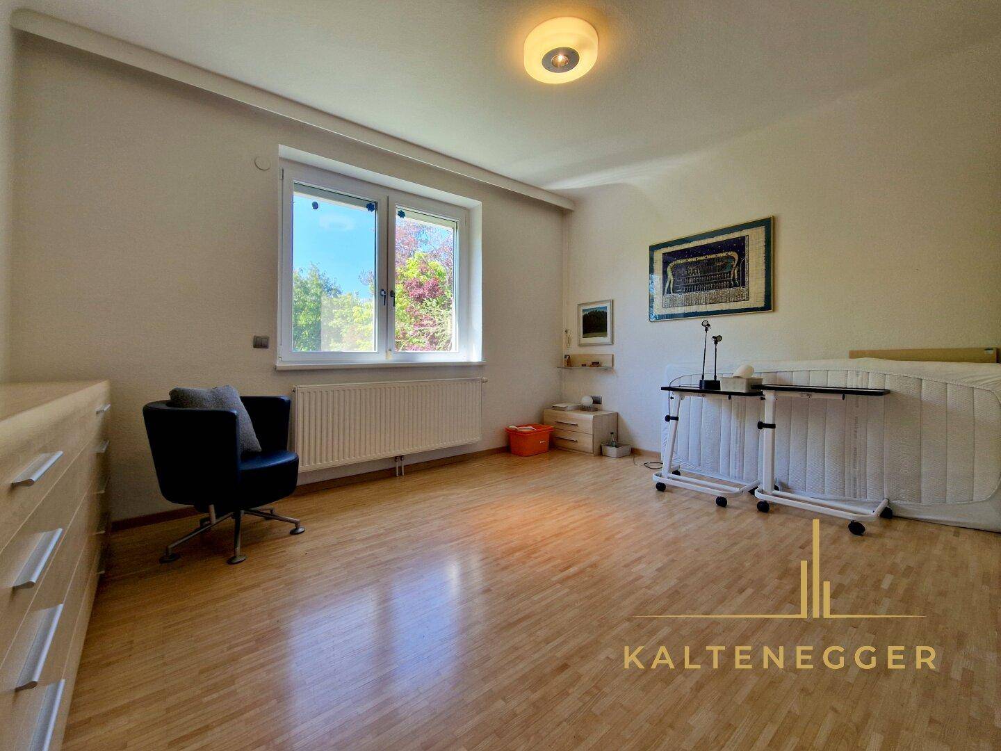 Helles Schlafzimmer mit Holzfußboden, großem Fenster und ausreichend Platz für individuelle Gestaltung.