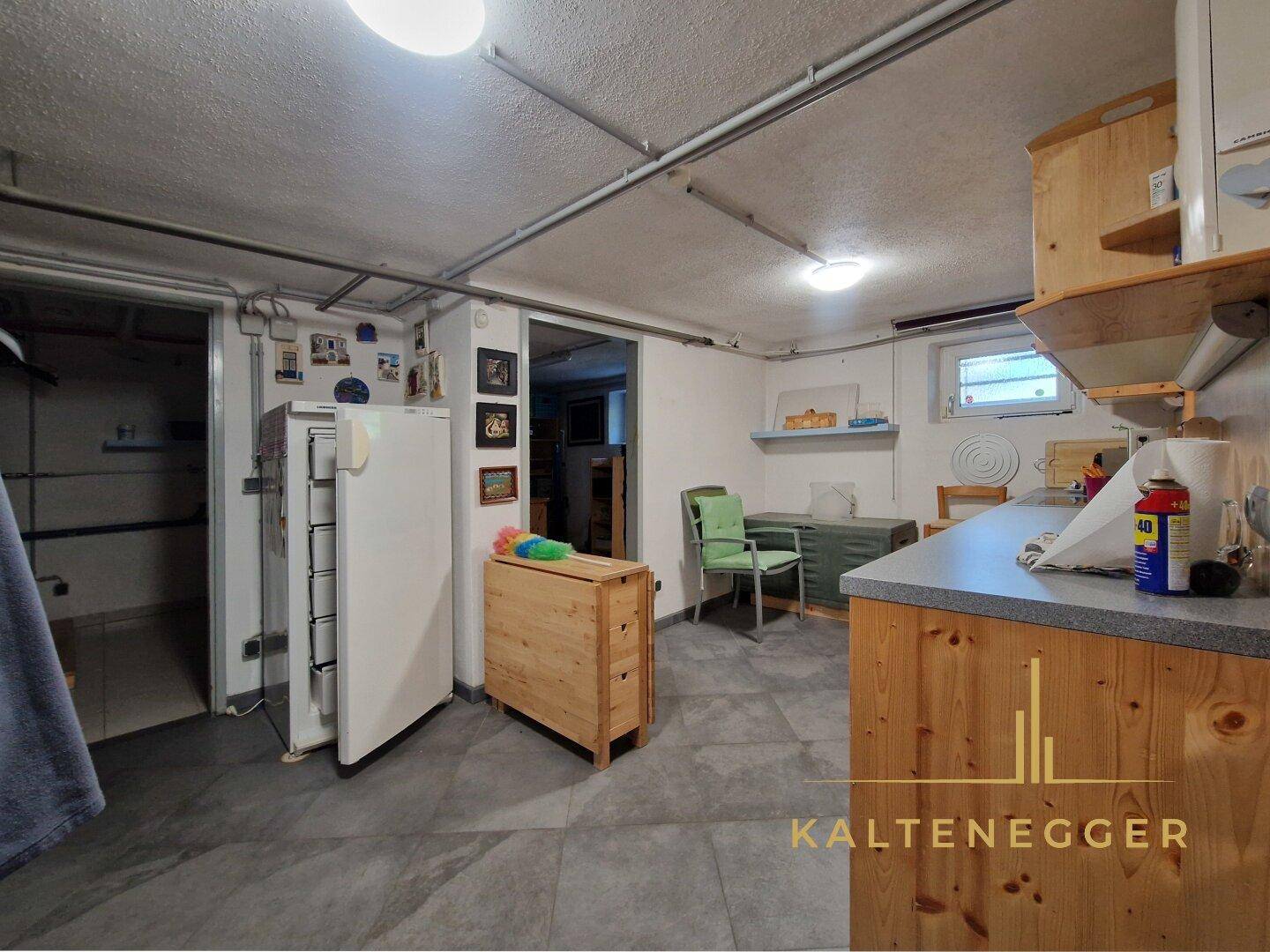 Geräumiger Kellerraum mit Kühlschrank, Arbeitsplatte und Stauraum, vielseitig nutzbar.