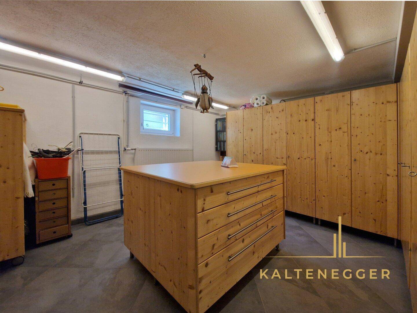 Großer Kellerraum mit zentraler Holzinsel und vielen Schränken für zusätzlichen Stauraum.