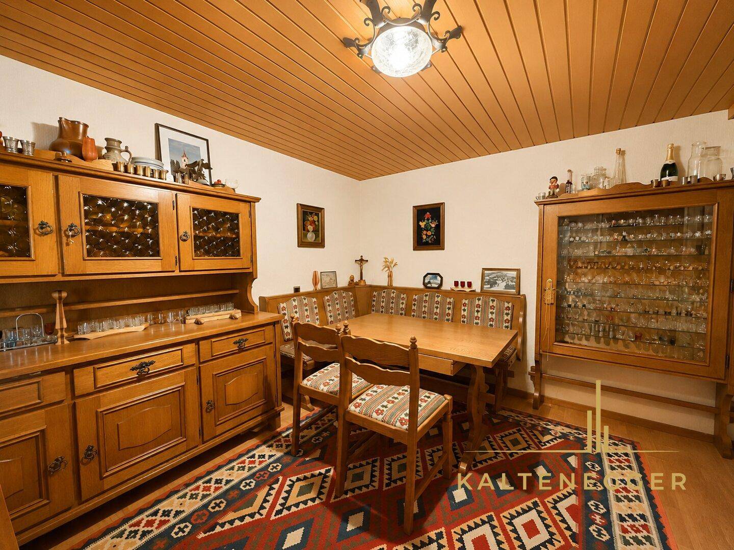 Traditioneller Essbereich mit Holzmöbeln, Holzdecke und farbenfrohem Teppich.