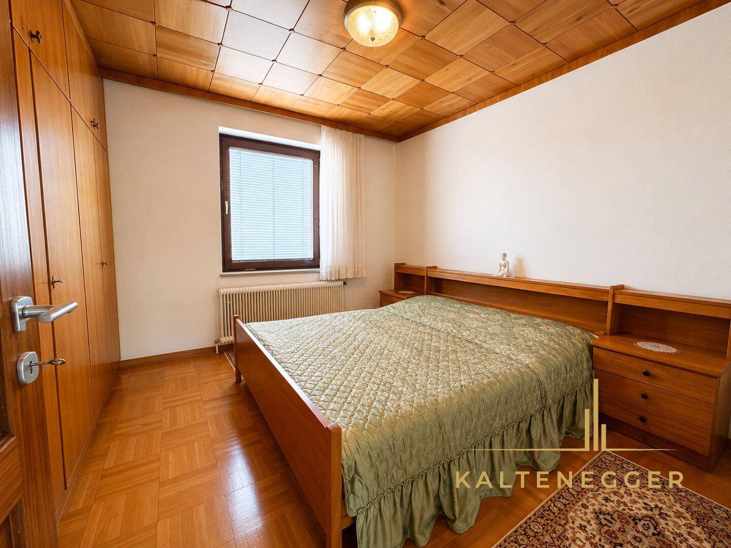 Gemütliches Schlafzimmer mit Holzdecke, Parkettboden und Einbauschränken.
