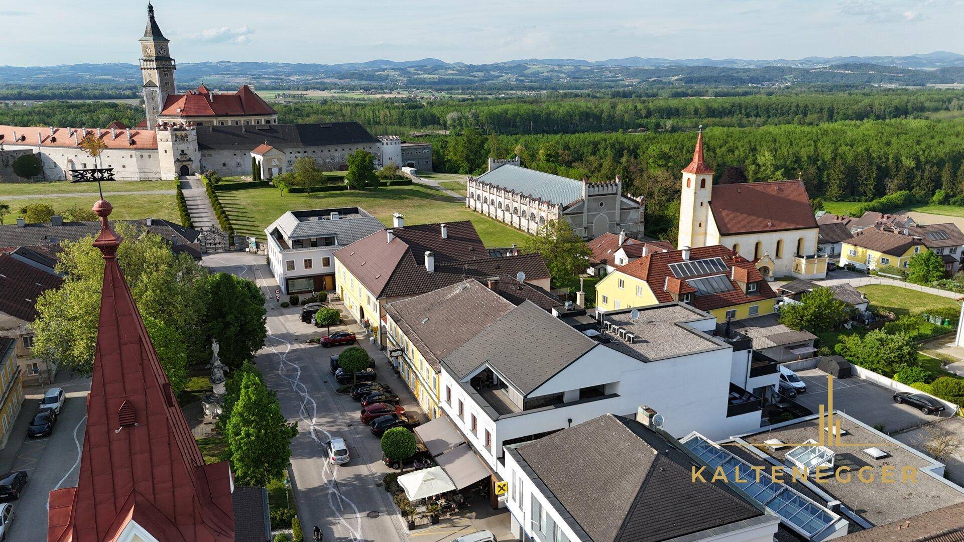 Weitläufige Luftaufnahme der historischen Ortschaft mit Schloss, Kirche und dem Anwesen in der Mitte.
