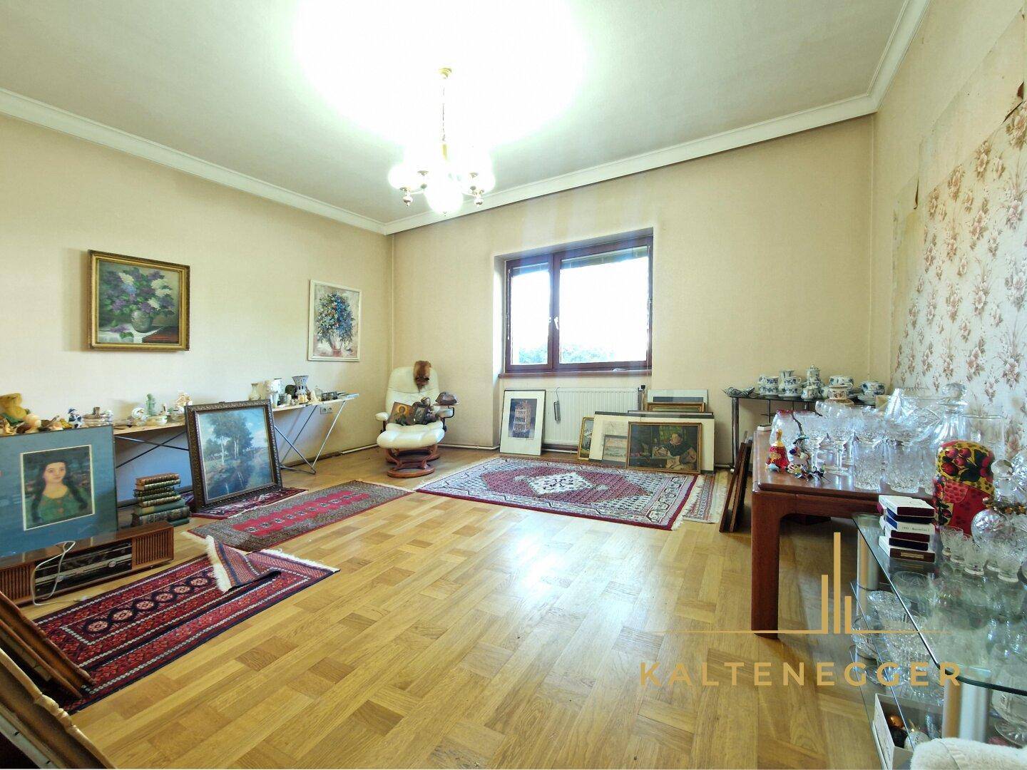 Geräumiges Zimmer mit Parkettboden, Holzdecke und verschiedenen Dekorationsgegenständen.