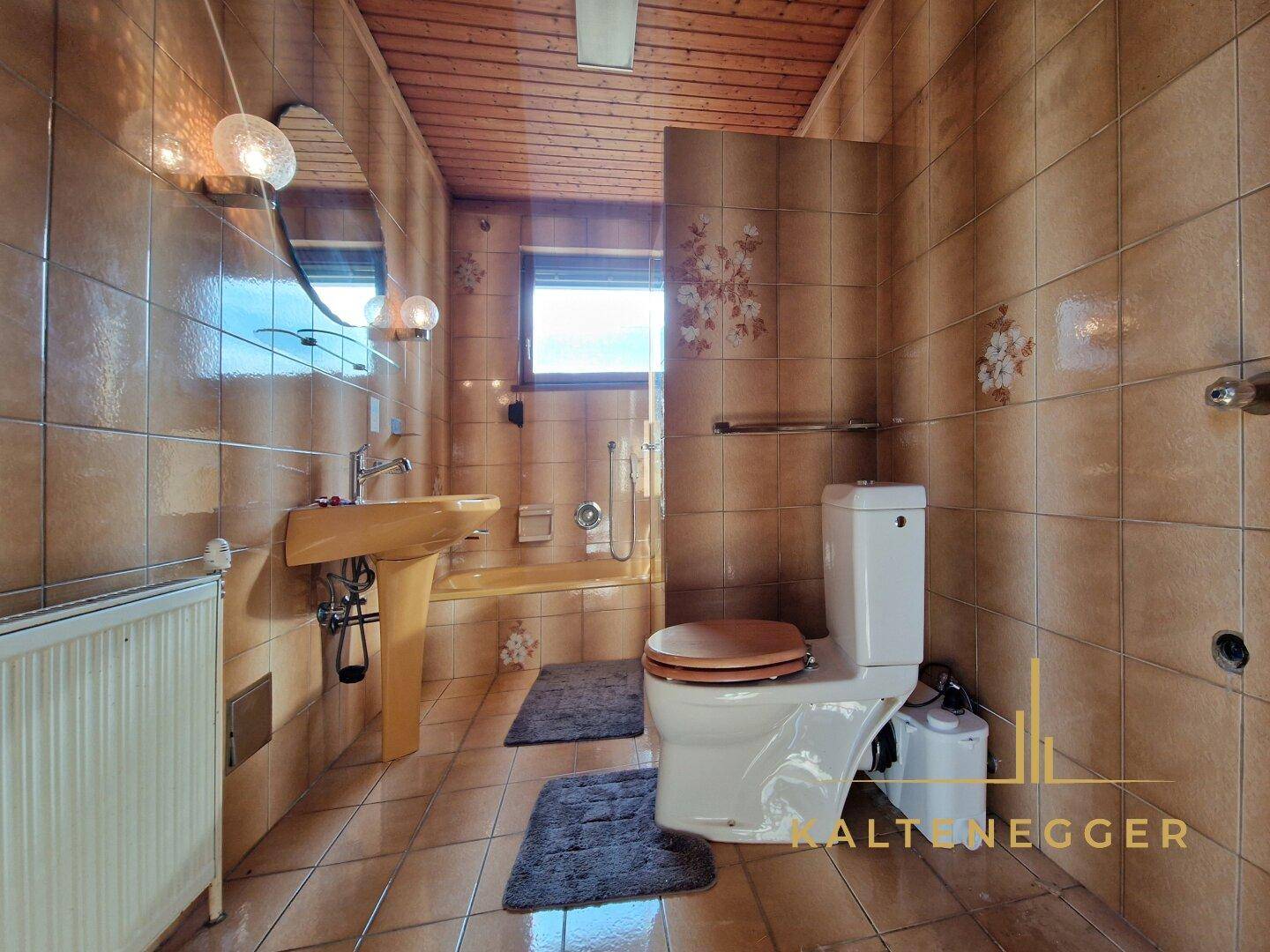 Badezimmer mit braunen Fliesen, gelbem Waschbecken, WC und Duschbereich.