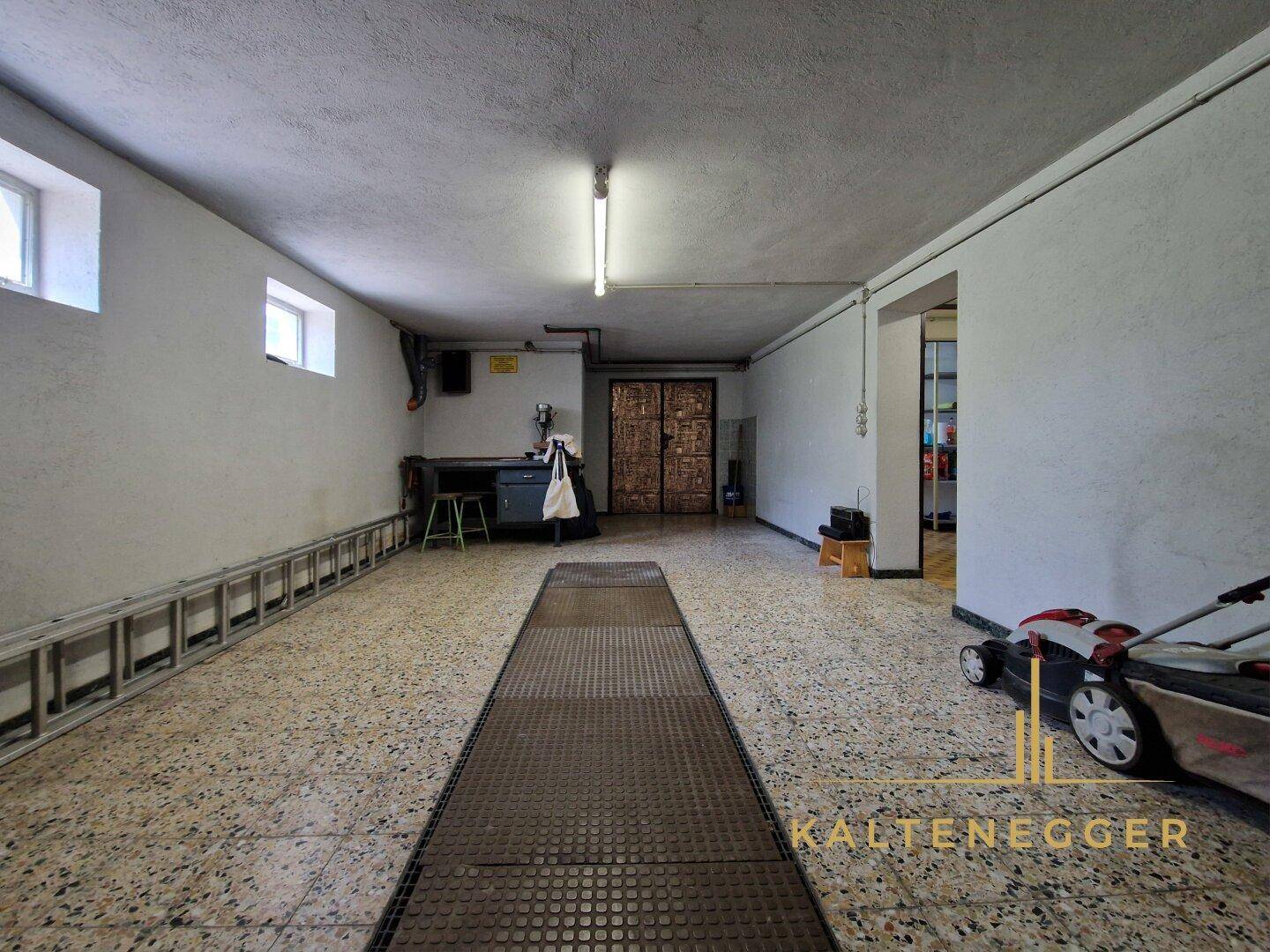 Geräumige Garage im Untergeschoss mit Werkbank und Terrazzoboden.