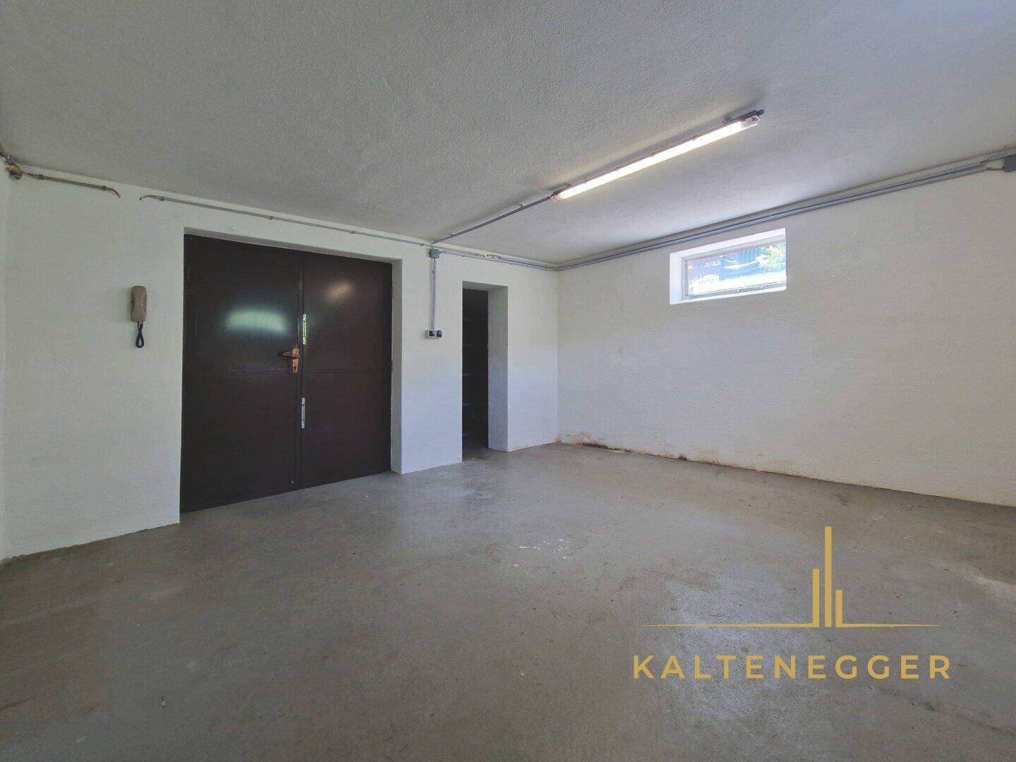 Leere Garage mit Betonboden und großen Doppeltüren für Fahrzeuge.