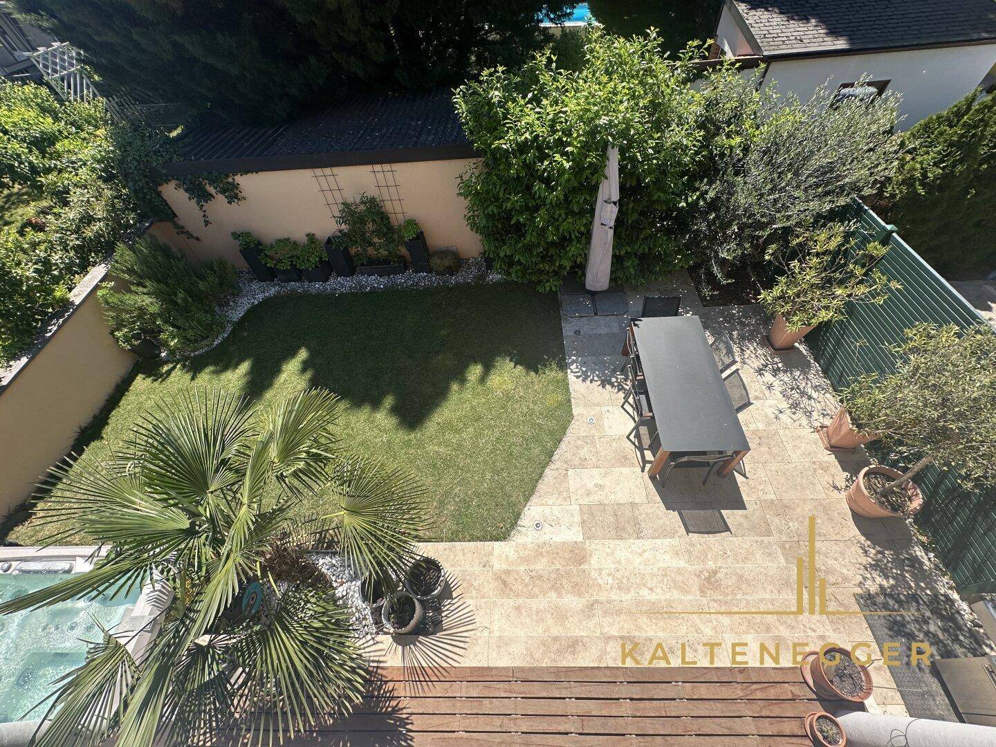 Vogelperspektive auf den gepflegten Garten mit Rasenfläche und Essbereich im Freien.