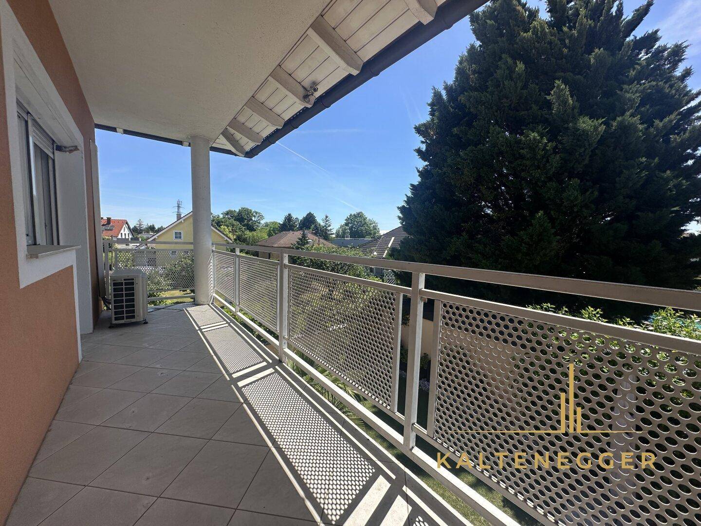 Geräumiger Balkon mit Fliesenboden und Metallgeländer, bietet einen weiten Blick ins Grüne.