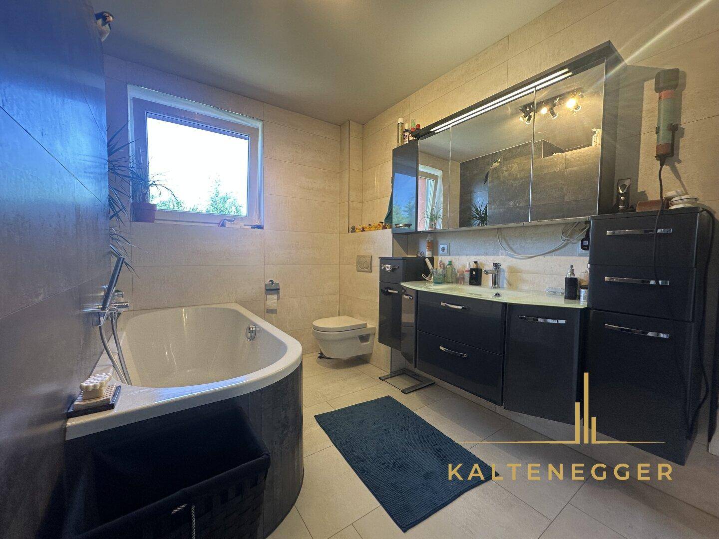 Modernes Badezimmer mit Badewanne, Doppelwaschbecken und großem Spiegelschrank.