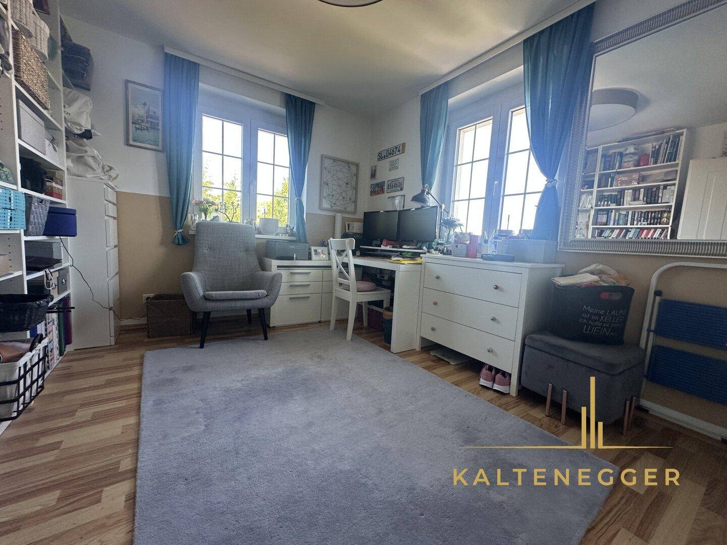 Helles Arbeitszimmer mit zwei Fenstern, Teppichboden und Regalen.