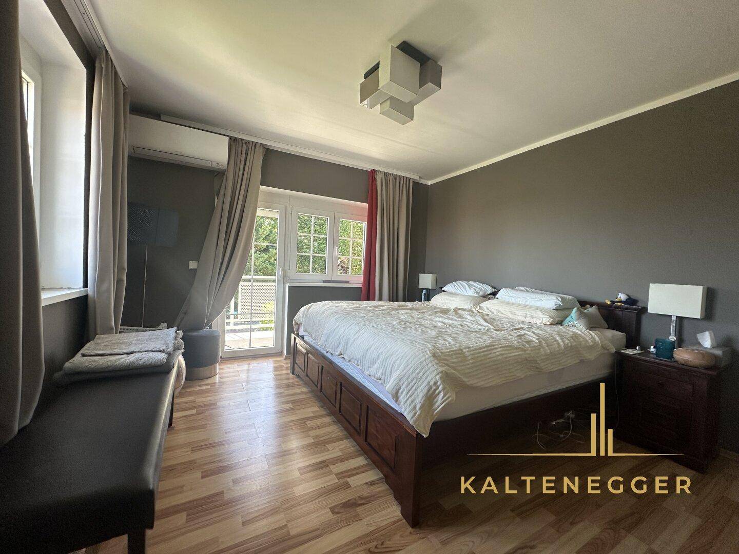 Schlafzimmer mit Holzboden, großem Bett und Zugang zu einem französischen Balkon.