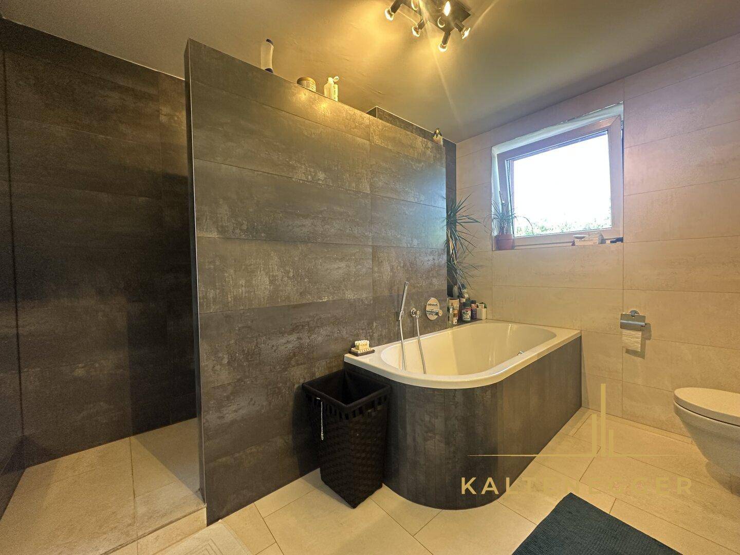 Modernes Badezimmer mit Badewanne, begehbarer Dusche und Fenster.