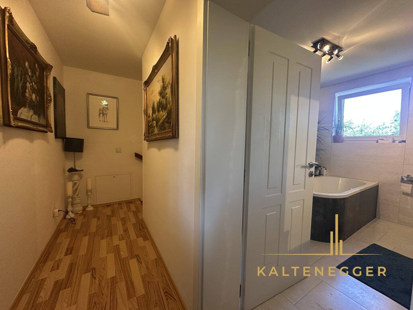 Flur mit Holzboden und Zugang zu einem modernen Badezimmer.