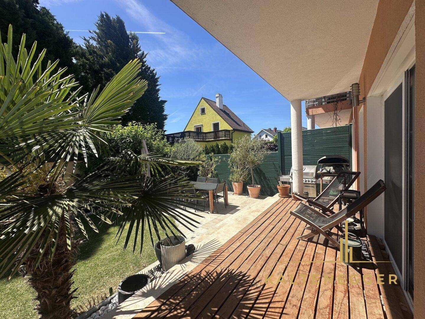 Überdachte Terrasse mit Holzdeck, Gartenmöbeln und Blick ins Grüne.
