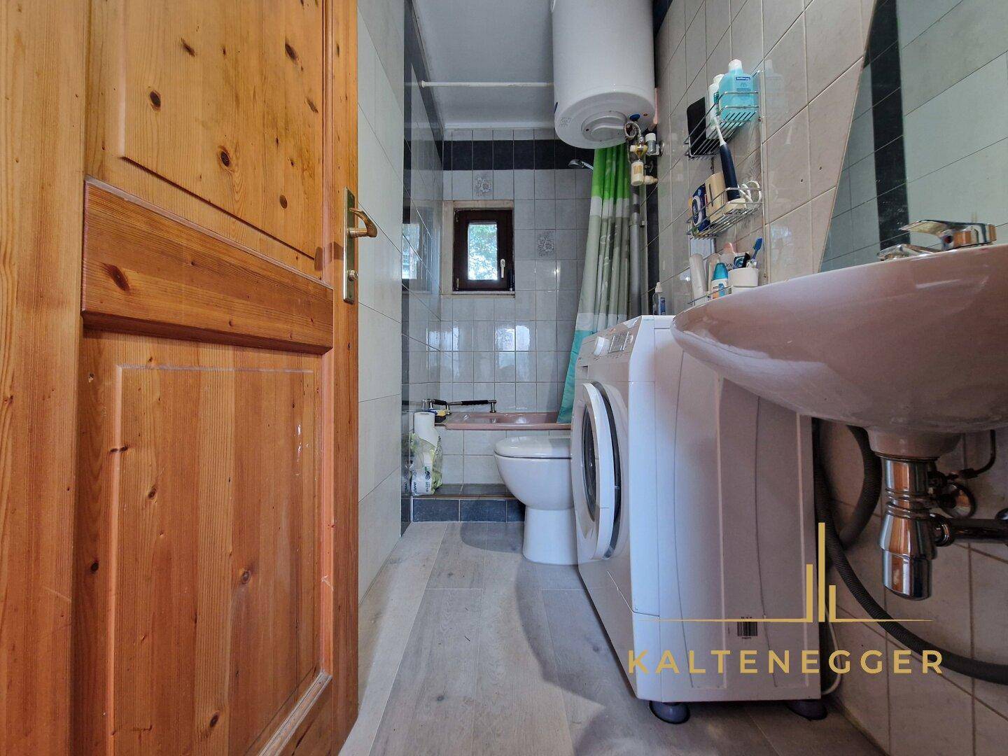Badezimmer mit Waschbecken, Toilette, Dusche und Waschmaschine.