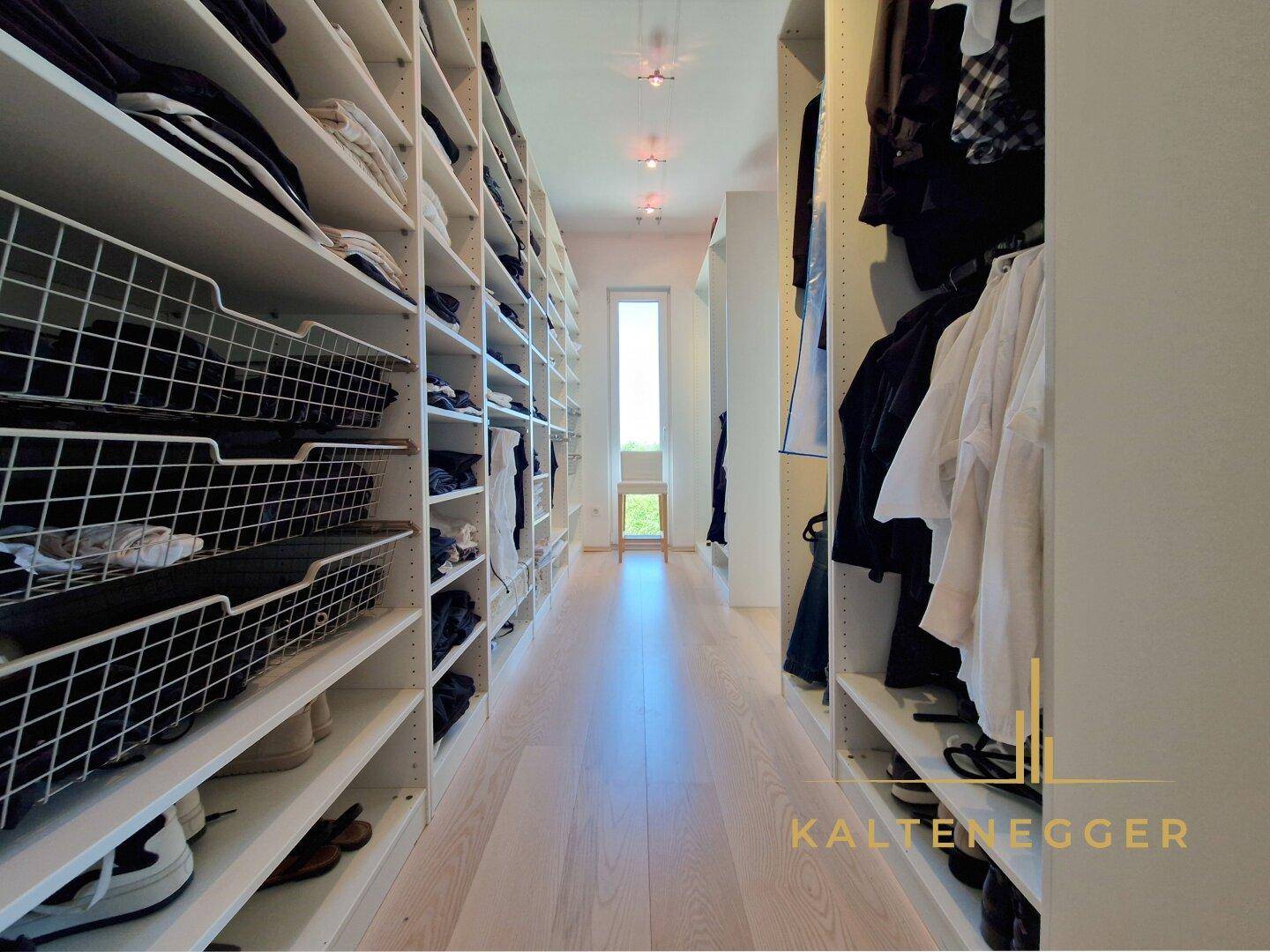 Geräumiger begehbarer Kleiderschrank mit vielen Regalen und Stauraum, gut beleuchtet.