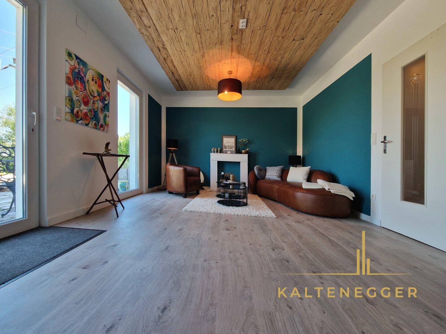 Stilvolles Wohnzimmer mit Holzbalkendecke, farbigen Wänden und gemütlicher Ledercouch.