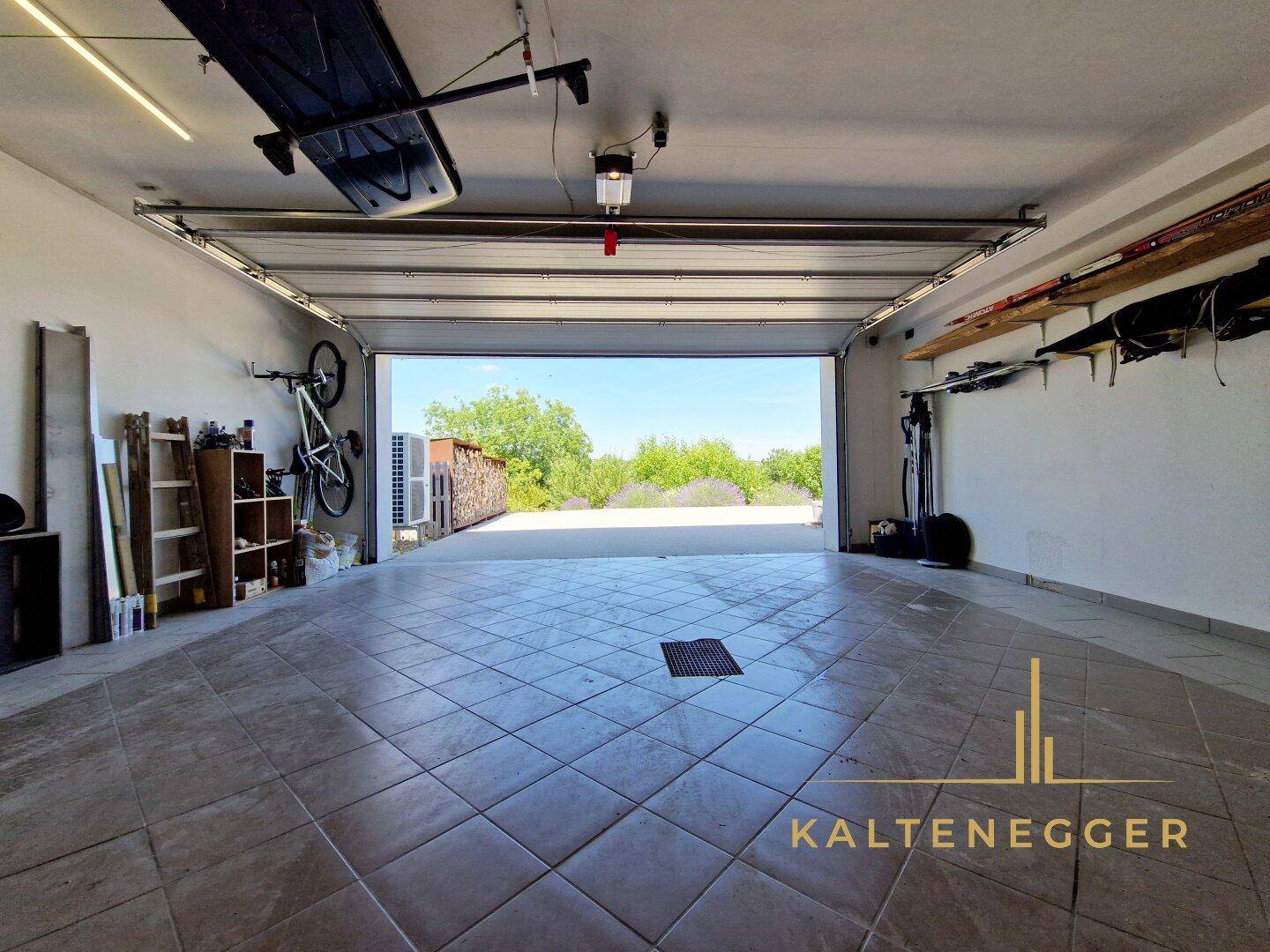 Geräumige Garage mit offenem Tor und Blick ins Grüne, bietet Platz für Fahrzeuge.