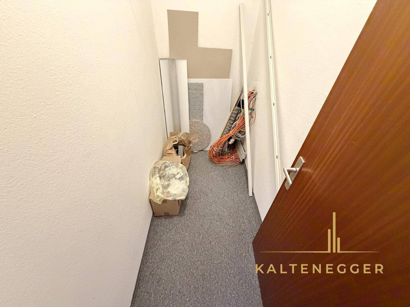 Abstellraum mit dunklem Teppichboden, in dem Baumaterialien und Kabel gelagert werden.