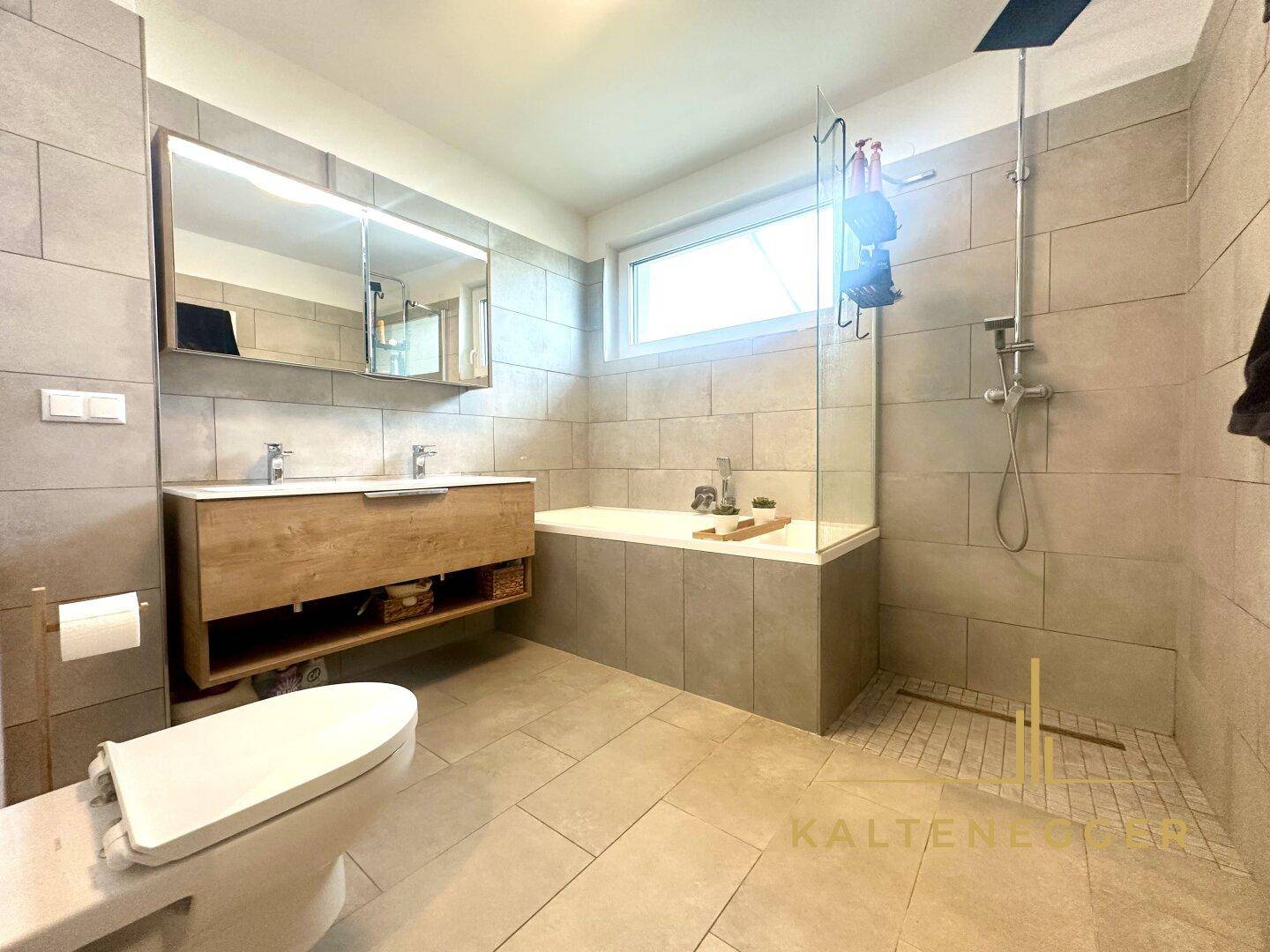 Geräumiges Badezimmer mit Badewanne, ebenerdiger Dusche und Wand-WC, ausgestattet mit modernen Armaturen.