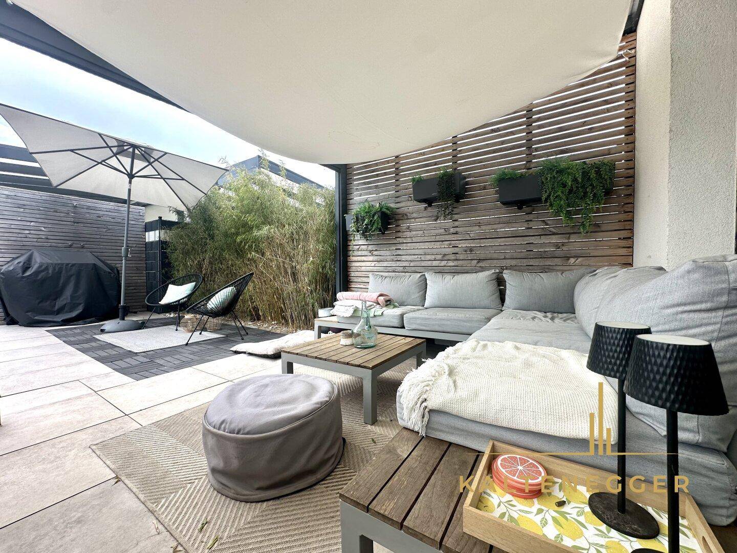 Gemütliche Lounge-Ecke auf der überdachten Terrasse mit bequemen Sofas und dekorativen Pflanzen.