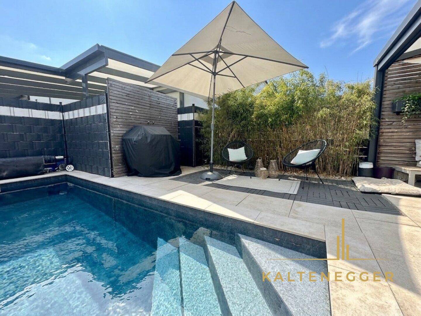 Gemütlicher Sitzbereich am Pool mit Sonnenschirm und modernen Gartenmöbeln, umgeben von Bambus.