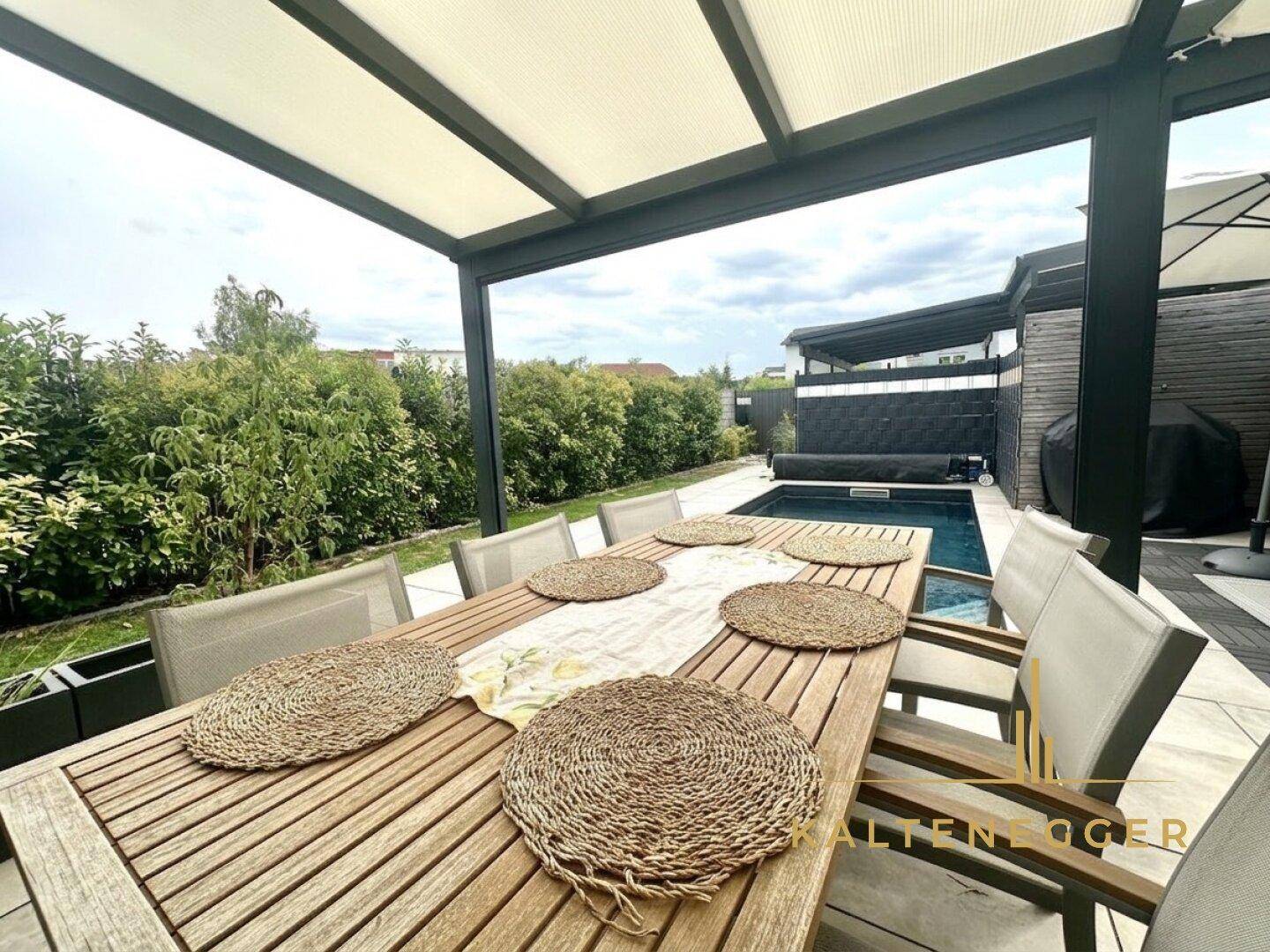 Geräumiger Essbereich auf der Terrasse unter einer Pergola, ideal für Mahlzeiten im Freien mit Blick ins Grüne.