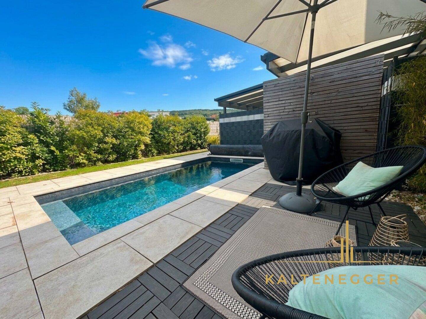 Sonniger Poolbereich mit bequemen Liegestühlen und einem großen Sonnenschirm für entspannte Stunden.